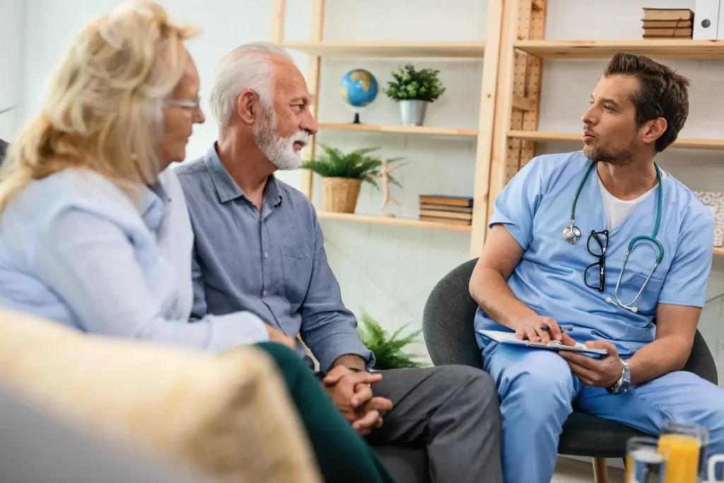 Healthcare worker discussing healthcare with senior couple during home visit.